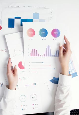 Close-up of hands analyzing colorful business data reports in an office setting.
